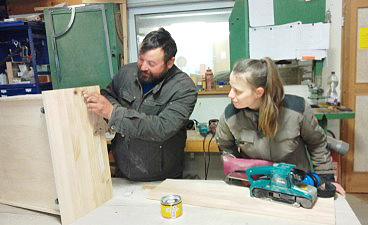 Ein Mann und eine Frau arbeiten in der Tischlerei an einem Holz-Werkstück