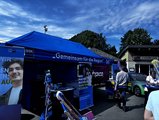 Foto: Blaues IHK-Zelt mit Info-Bannern zu Ausbildung und Beruf. Besucher informieren sich, Stadion im Hintergrund, sonniges Wetter, Auto neben dem Stand.