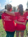 Rückenansicht des Laufshirts Rückenansicht zweier Läuferinnen, Arm in Arm, samt Laufshirts mit Motivationsspruch