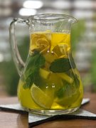 Zu sehen ist die Nahaufnahme eines Glaskruges. Sie enthält Ingwer, Limetten und Minze.