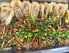In der Nahaufnahme ist ein Gericht aus Reisnudeln, gebratenem Tofu und Bok Choi zu sehen.