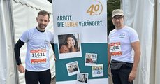 Foto: Zwei Kollegen mit Ticket für schnellen Läufer vor dem Roll-up „40 Jahre faw“