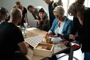 2 Besucher*innen probieren sich unter Anleitung einer Mitarbeiterin im Berufsfeld Holz aus