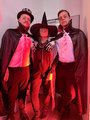 Foto: Drei Menschen, verkleidet als Vampire und Hexe stehen in rotem Licht.