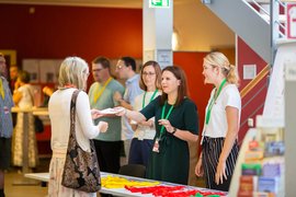 Inhaltsbild: Infostand mit mehrere Personen, die miteinander kommunizieren.