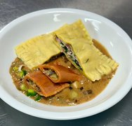 Zu sehen ist ein angerichteter Teller mit hausgemachten Ravioli, die mit einer Pilzrahmsauce serviert werden.