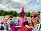 Foto: Tretbootfahrt auf dem See. Vier fröhliche Menschen drehen sich in einem Flamingo-Tretboot für ein Selfie lachend zur Kamera. 
