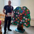 Jahreszeitenbaum Foto: Ein Berufstrainer steht mit einer Schachtel Pralinen vor dem Jahreszeitenbaum.