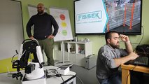 Foto des beiden Mitarbeiter der Firma Fissek. Einer steht vor dem Whiteboard, der andere sitzt vor dem Laptop. 