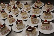 Foto: auf dem Foto sind viele kleine Teller zu sehen auf den sich je ein Stück Erdbeer-Sahne-Torte befindet.