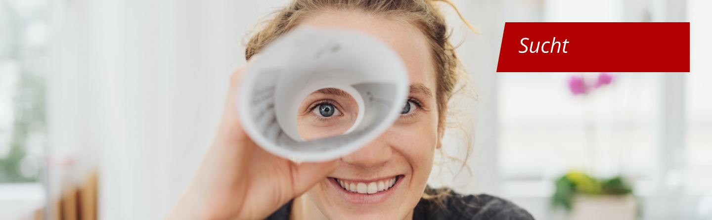 Symbolbild Sucht: Eine Frau blickt durch ein zusammengerolltes Papier wie durch ein Teleskop