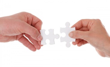 Jetzt bewerben! Zwei Hände stecken zwei Puzzle-Teile zusammen.