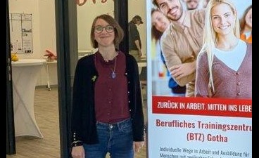 Frau Weber, Auszubildende im BTZ Gotha Foto: Frau Weber, Auszubildende im BTZ Gotha neben einem BTZ-Rollup. Dahinter weiß bespannte Stehtische.
