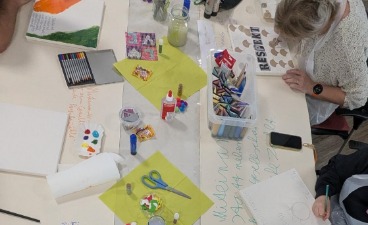 Kreatives Arbeit im BTZ Gotha Foto: Blick auf einen mit verschiedenen Schreib- und Bastelmaterialen bestückten Schreibtisch, an dem Menschen kreativ sind.