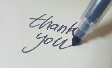 Stift schreibt Dankeschön auf Englisch auf ein Blatt Papier