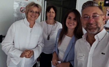 Foto: Vier Personen stehen nebeneinander und lachen in die Kamera.