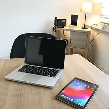 Aufgeklappter Laptop und iPad einsatzbereit auf einem Tisch.