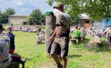 Abschlusstag 2025 der Erstausbildung Foto vom Abschlusstag 2025 der Erstausbildung. Zu sehen ist ein Falkner mit einem Greifvogel auf dem Arm, umringt von Zuschauer*innen.