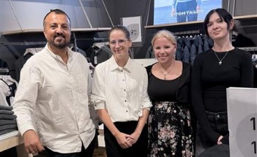 Drei Teilnehmende stehen gemeinsam mit ihrem Ausbilder im Ladengeschäft