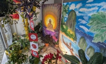 Draufsicht auf das dekorierte Schaufenster. Zu sehen ist ein Bild eines Strandes, sowie eines Buddhas. Im Vordergrund befindet sich Sand und verschiedene Pflanzen