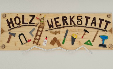 Foto des Endproduktes: Ein Holzschild, auf dem Holz-Werkstatt steht, verziert mit verschiedenem Werkzeug.