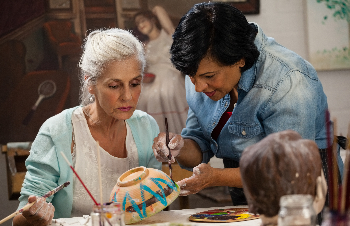 Das Bild zeigt zwei Frauen in einer Kreativ-Werkstatt, die gemeinsam eine Keramikschale bemalen. 
